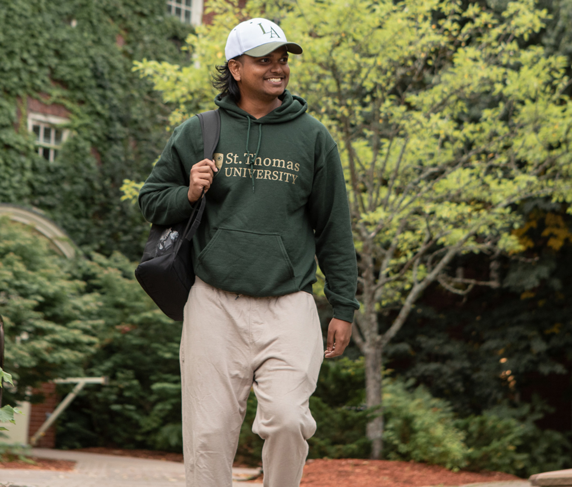 A male student wearing a green St. 糖心传媒_糖心vlog_糖心vlog 在线s hoodie walks through campus